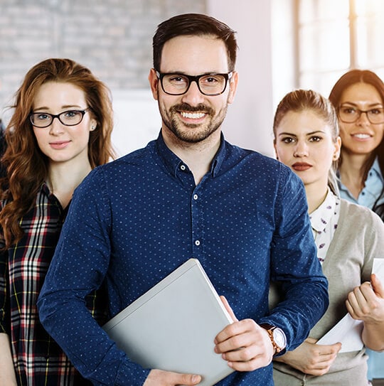 Smiling male insurance professional in glasses holding a laptop, with his team