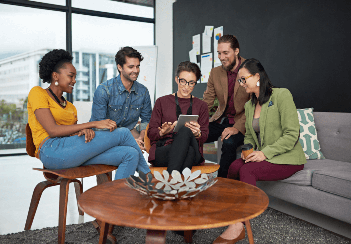 five diverse insurance agent colleagues collaborating around a tablet in a modern office