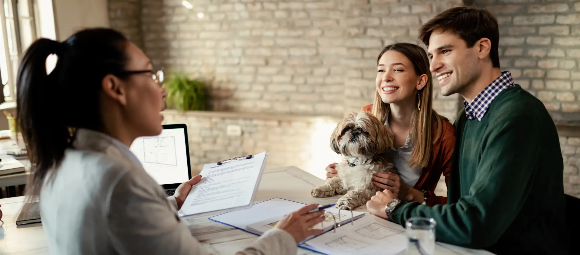smiling couple with their dog talking to an insurance producer about getting a pet insurance policy