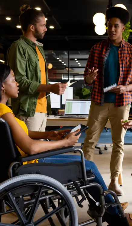 three insurance agent colleagues, including a woman in a wheelchair, collaborating in a modern office discussion