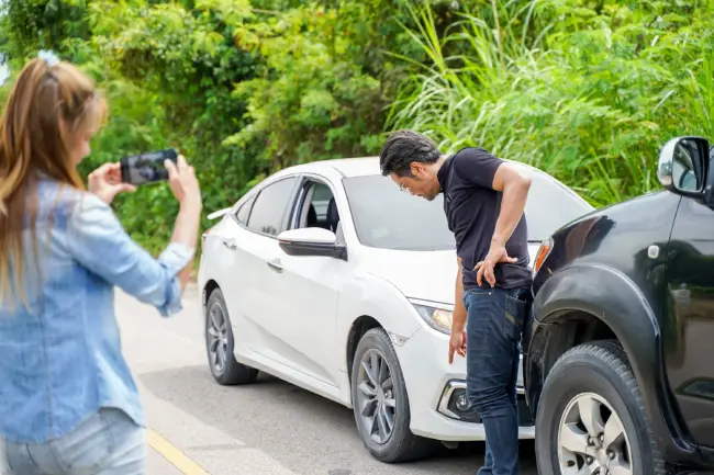 Drivers documenting damage at the scene of a car accident for an insurance claim