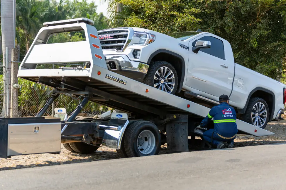 roadside assistance professional loading a white pickup onto a tow truck