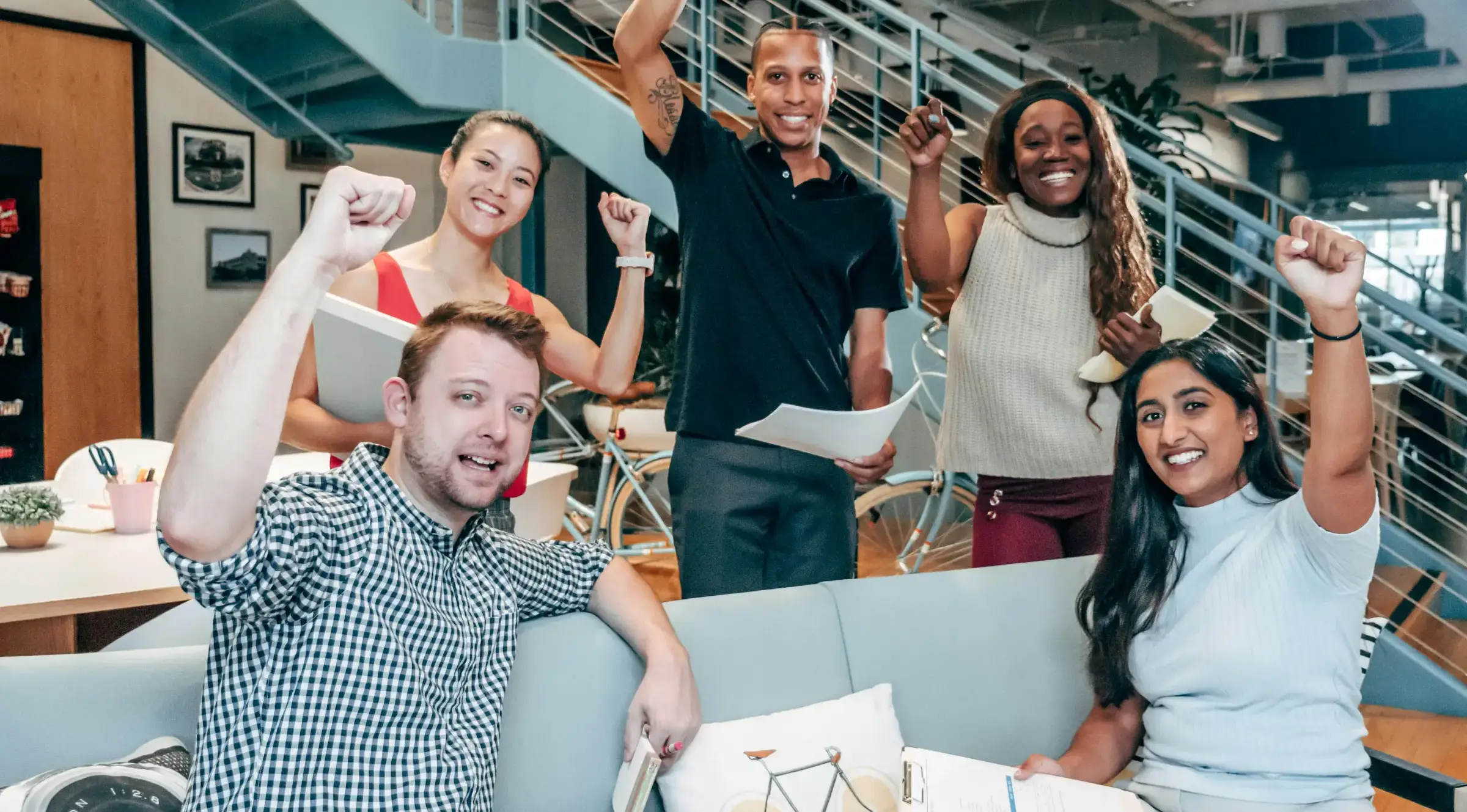 happy insurance producer team cheering and celebrating success in a modern office