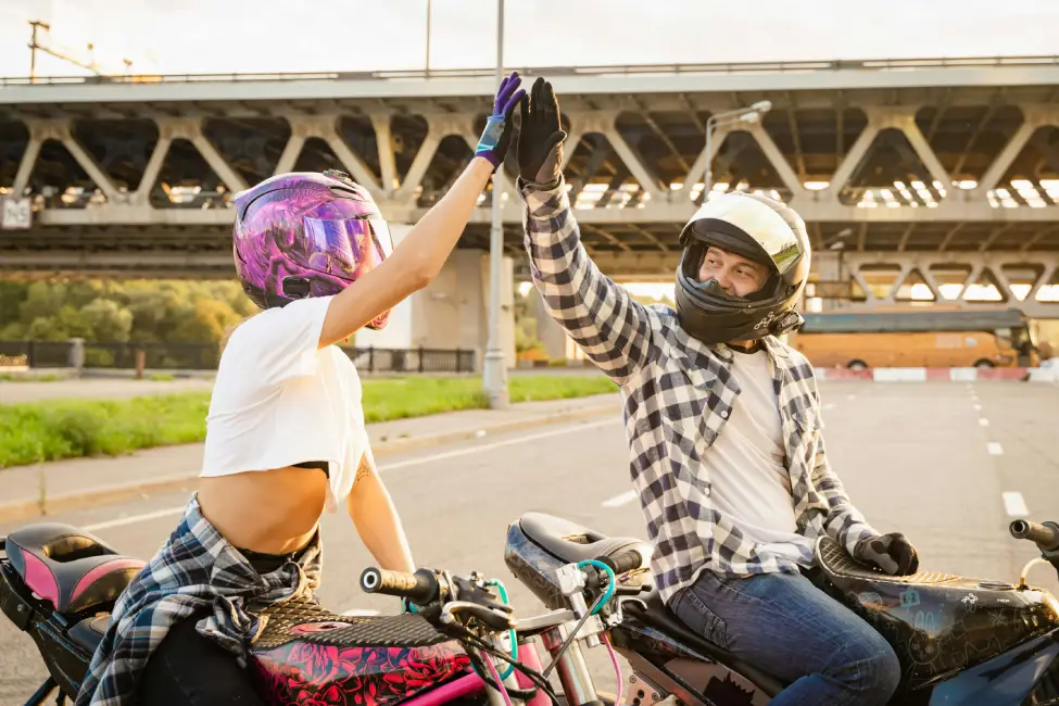 two motorcycle riders high-fiving because they found a great motorcycle insurance deal through Vireya