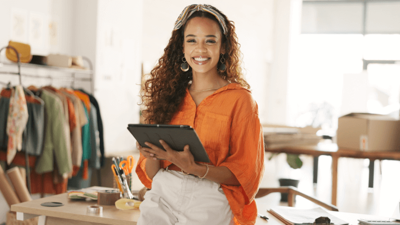 woman with a tablet smiling in her clothing store because she has hassle-free insurance from Vireya new